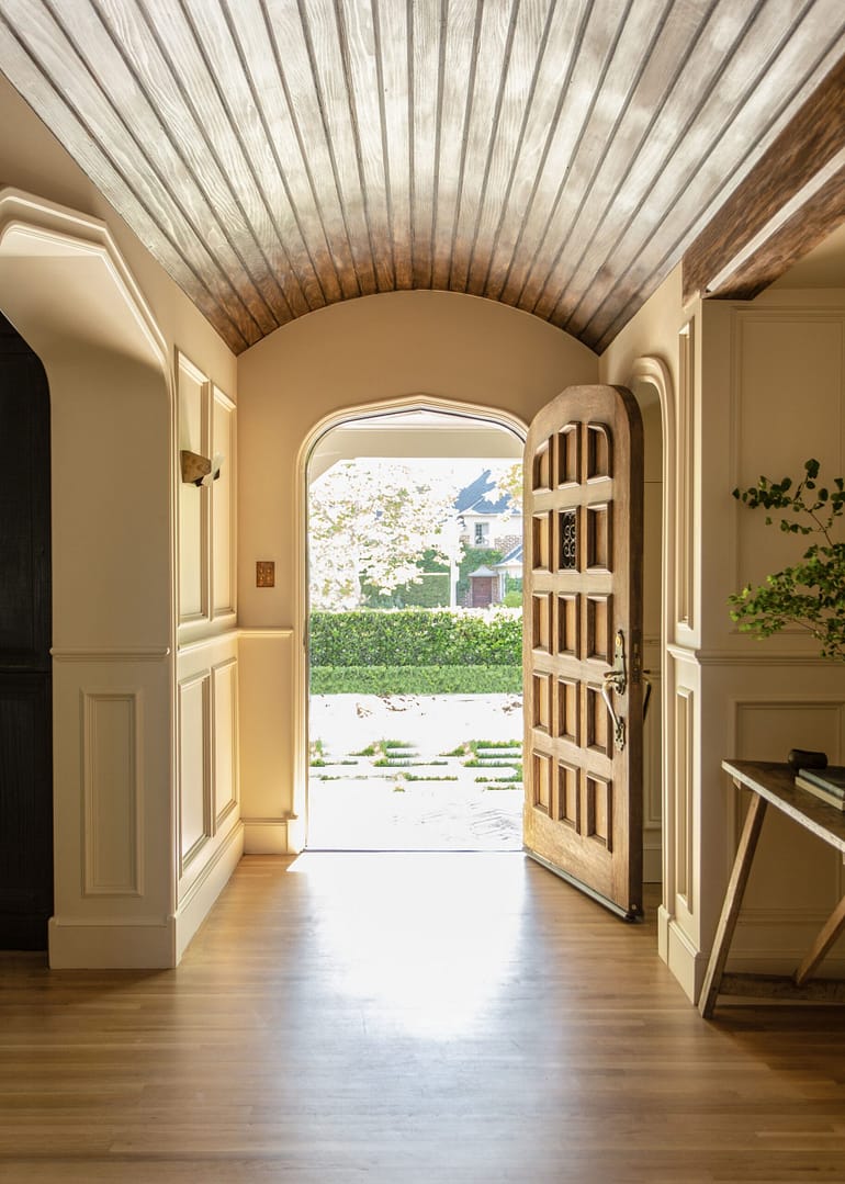 A hallway with a wooden door and a wooden ceiling.