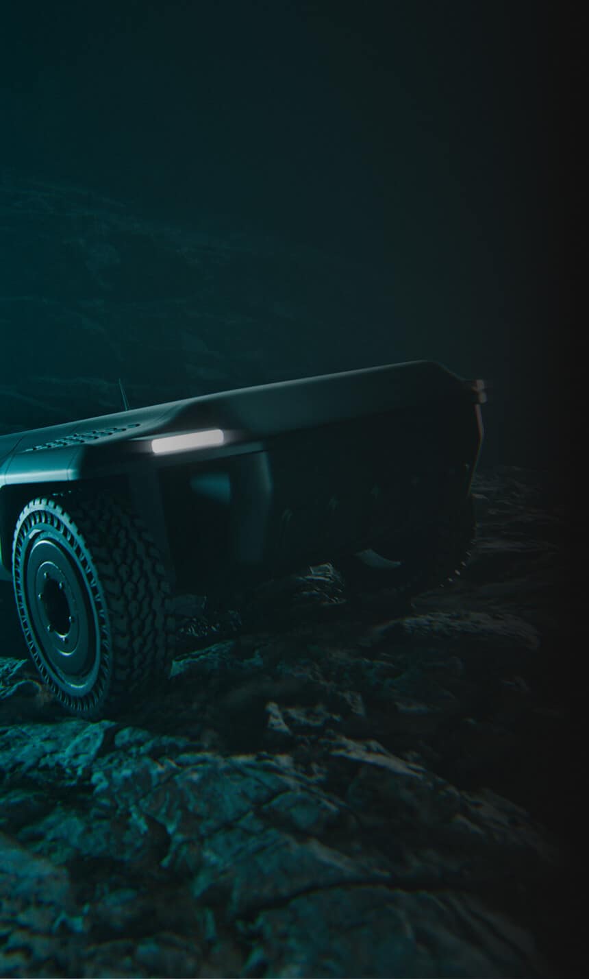 A rugged, futuristic, black autonomous rover with large wheels and LED lights drives over rocky terrain in dim, moody lighting.