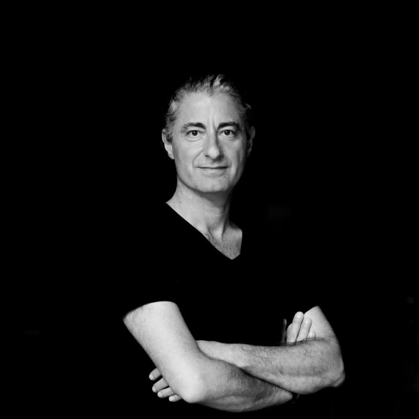 A black and white photo of a man with his arms crossed.