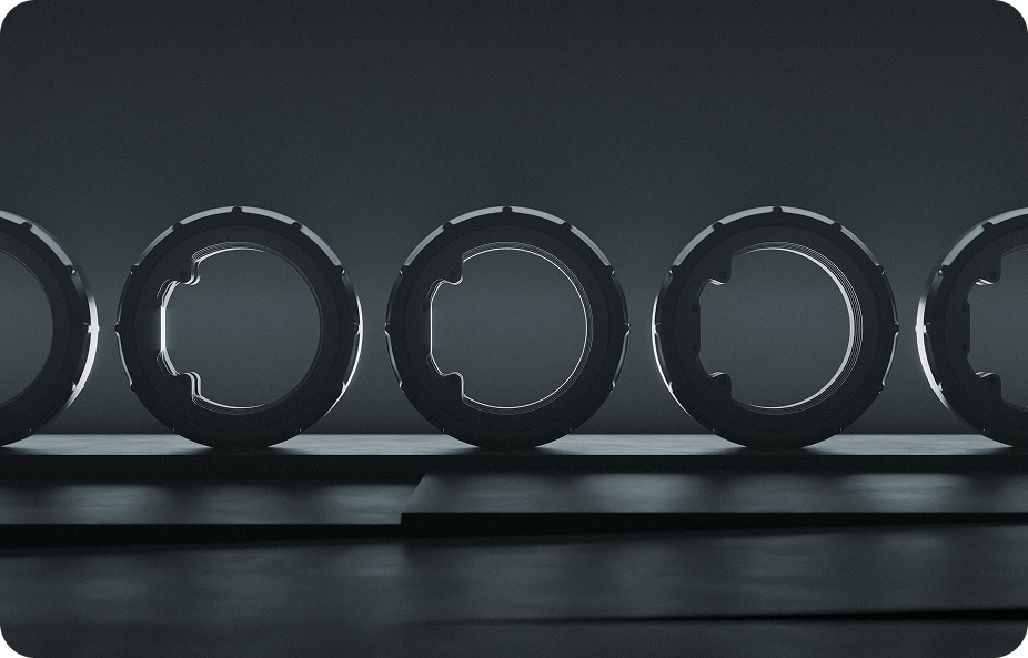 A grayscale image showing a row of five circular, metallic structures aligned on a flat surface. The shapes are evenly spaced and partially illuminated, casting shadows on the ground. The background is dark and minimalistic.