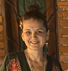A woman smiling in front of a brick wall.